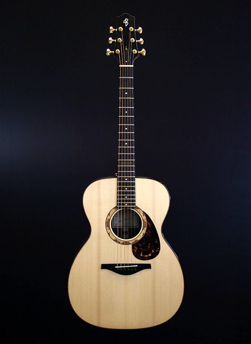 Front of OM guitar against dark background made by luthier Oska Burman